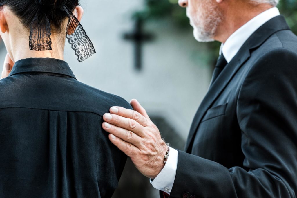 Ausgeschnittene Ansicht eines Mannes, der eine Frau bei der Beerdigung berührt