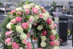 Blumenkranz mit weißen und rosafarbenen Rosen auf dem Freidhof