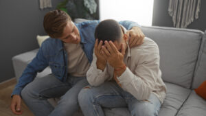 Mann tröstet seinen verzweifelten Freund im Wohnzimmer