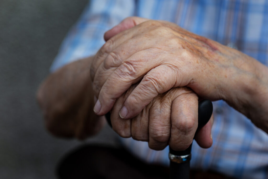 Hände übereinander gelegt über Gehstock